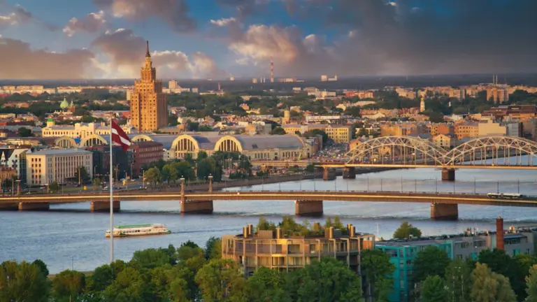 Gaisa skats uz Rīgas vēsturisko centru ar Daugavas tiltu un pilsētas panorāmu.