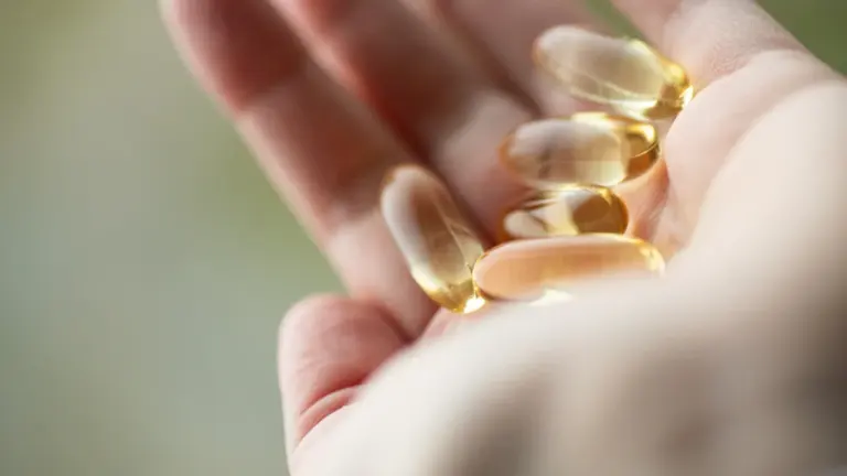 Cilvēks tur plaukstā D vitamīna kapsulas pirms došanās pie ārsta konsultācijas.