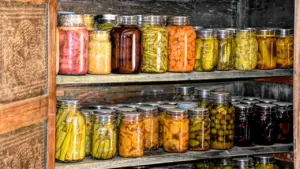 Tradicionāla sakņu glabātuve ar stikla burkās konservētiem dārzeņiem uz koka plauktiem.