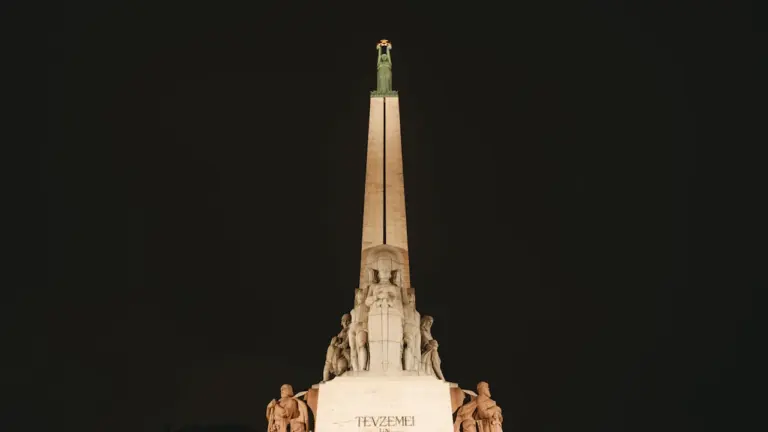 Brīvības piemineklis Rīgā naktī, izgaismots pret tumšām debesīm, simbolizē Latvijas valstisko neatkarību.