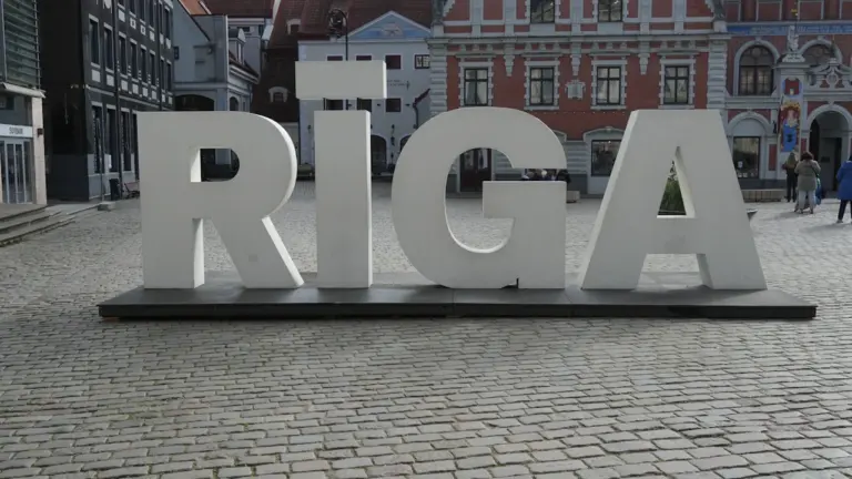 Liels, balts uzraksts RĪGA uz bruģēta laukuma Rīgas vecpilsētā dienas laikā.