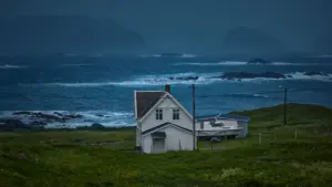 Balta koka māja krastā pie jūras gaidāmās vētras laikā, Norvēģija.