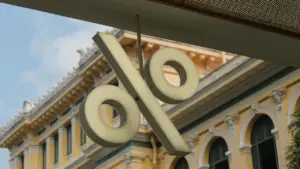 Procentu likmes simbols pie ēkas fasādes, kas simbolizē banku darbību un ekonomiskos lēmumus.