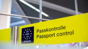 Dzeltena norāde lidostā ar uzrakstu pasu kontrole latviešu un angļu valodā.
