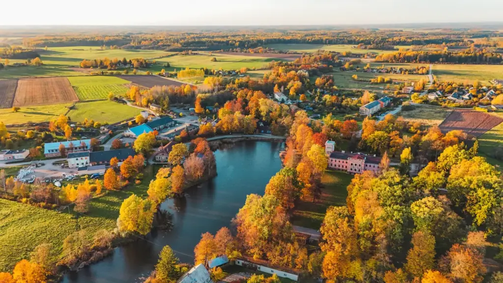 Latvijas mazpilsēta un upe rudens krāsās no putna lidojuma skatpunkta