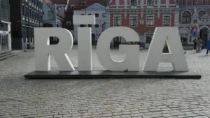 Liels Rīgas pilsētas uzraksts uz bruģētas ielas vēsturiskajā centrā dienā.