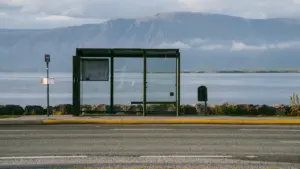 Vientura autobusa pietura pie ūdenskrātuves ar kalniem fonā rīta gaismā
